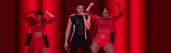 El cantante Luca Hänni con dos bailadoras en un escenario iluminado de rojo