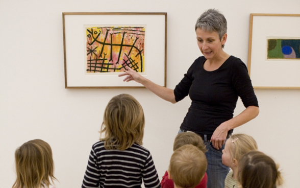 Une femme explique un tableau à un groupe d'enfants