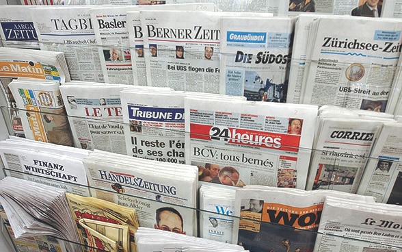 Various newspapers on a newspaper stand.