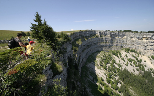 一家人从令人头晕目眩的峭壁之上俯瞰纳沙泰尔州的马蹄谷（Creux du Van）。