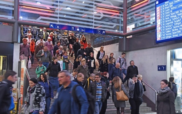 People walking down a busy stairway in a railway station.