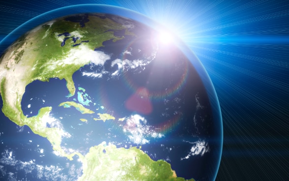 Symbolic image: sun behind planet earth.
