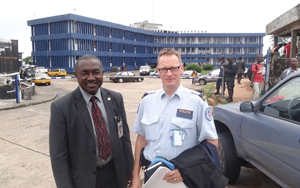Il vicecapo del dipartimento anticrimine della polizia nazionale liberiana e l’esperto di polizia Laurent X. posano davanti al quartier generale della polizia nazionale in Liberia.