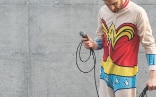 Schauspieler Bene Greiner im Wonder Woman Kostüm mit einem Mikrofon in der Hand, dessen aufgerolltes Kabel an ein Lasso erinnert.