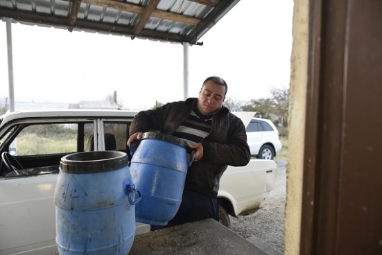 Kakha is handing over a big milk container