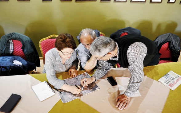 Due uomini e una donna consultano una carta. 