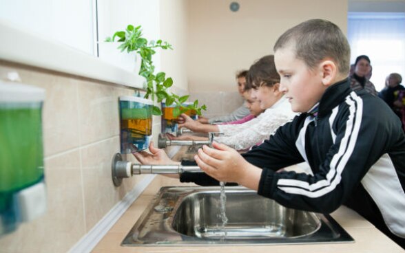 Image of boys and girls washing their hands in the EcoSan restroom