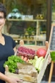 Biljana, co-founder of The Good Earth organic cooperative, holding a basket of organic fruit and vegetables.