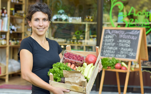 Biljana, co-fondatrice di «The Good Earth», mostra un cesto di frutta e verdura biologici.