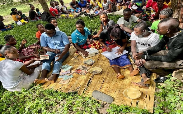 'Patience Pays' Savings Group conducting their regular meeting in Katete, Eastern Zambia while members of the community look on.
