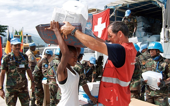 Ein Mitglied des Schweizerischen Korps für Humanitäre Hilfe (SKH) verteilt Hilfsgüter.