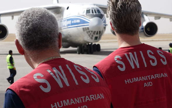 Due membri del Corpo svizzero di aiuto umanitario davanti all'aereo cargo all'aeroporto di Erbil.