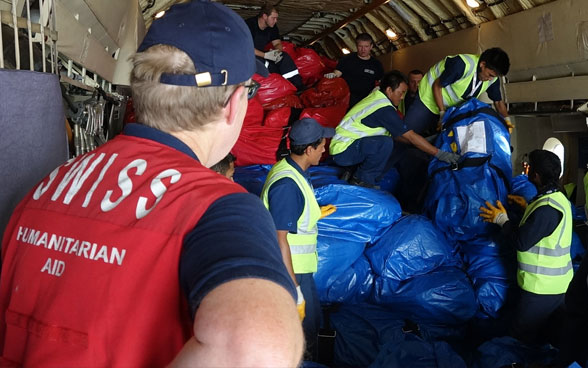 Un membre du Corps suisse d’aide humanitaire à l’intérieur de l’avion-cargo observe le déchargement de la cargaison.