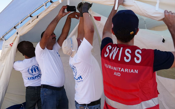 Un membro del CSA e tre membri del CICR mentre montano una tenda. 