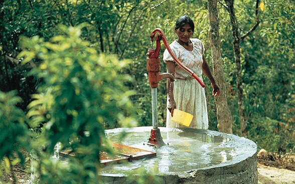 Eine Frau in Honduras schöpft Wasser aus einem Brunnen.
