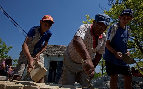 Abitanti rom costruiscono un muro in mattoni