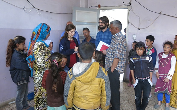 Stefan Bumbacher, begleitet von einer Mitarbeiterin des WFP, im Gespräch mit einer Gruppe Vertriebener.