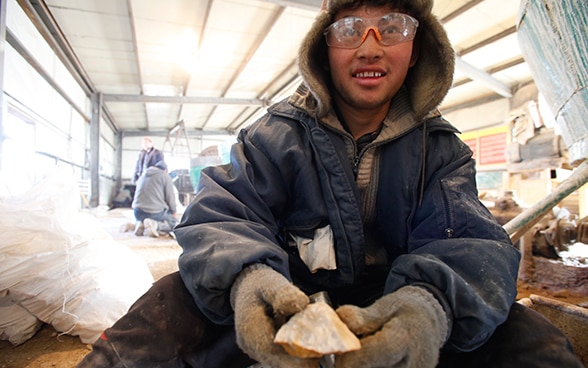 Ein junger Bergarbeiter zeigt ein Stück Golderz.