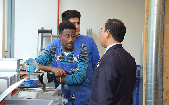 Two young men training to be building and automotive systems technicians talk to a member of a foreign delegation at the Swiss Technical College in Winterthur. 