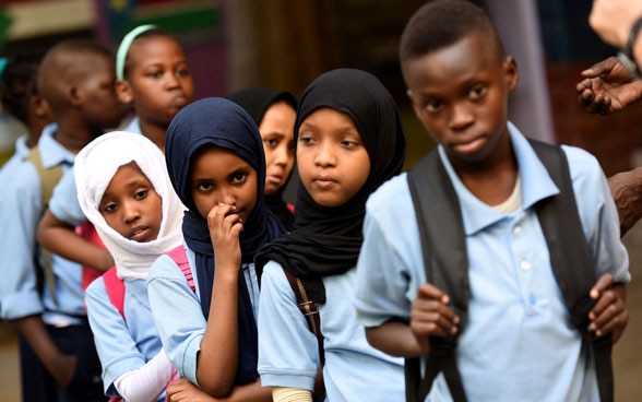 Kinder und Jugendliche verschiedener Nationen gehen in einer Reihe hintereinander her.