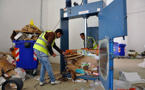 Due persone si occupano dei rifiuti di carta e di cartone nel centro di riciclaggio di un Comune albanese.