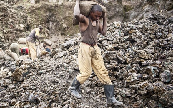 Un trabajador de una mina de cobalto en la provincia de Katanga, en Congo, transporta dos sacos de mineral recién extraído (13.01.2011).