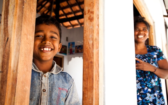 Un niño y una mujer posan sonrientes en su casa reconstruida.