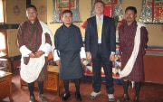 Drei bhutanische Beamte in traditionellen Kleidern mit einem westlichen Gast.