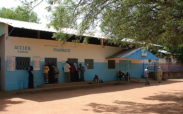 Groups of people standing in front of various counters at a hospital in Chad.