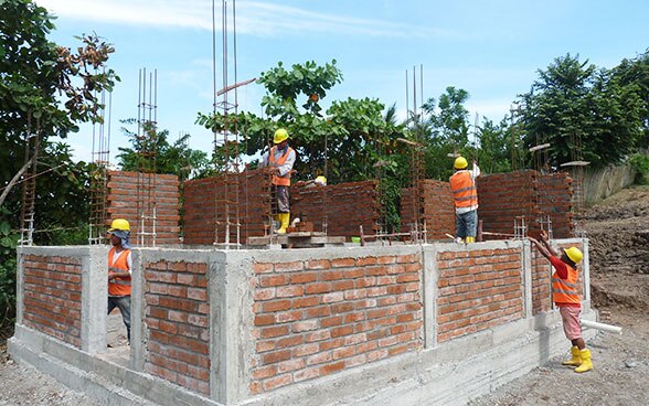 Bricklayers building the walls of a house.