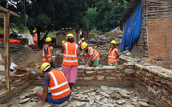 Nepalesische Frauen und Männer beim Bau von Hausmauern.