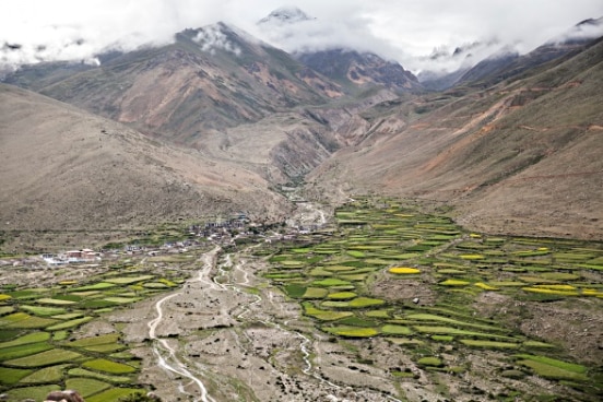 Landscape with village, fields and river at the foot of the mountains