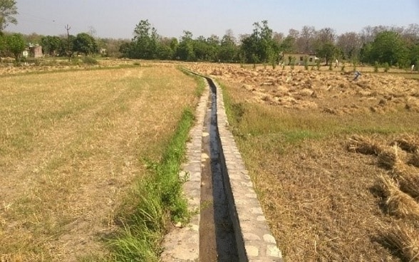 Freshly repaired irrigation channel flowing through two dry fields