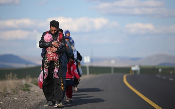 Eine Flüchtlingsfamilie geht eine Straße entlang