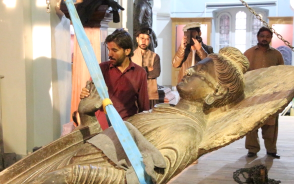 La statua di Buddha viene spostata dalla parete con l’ausilio di una cinghia.