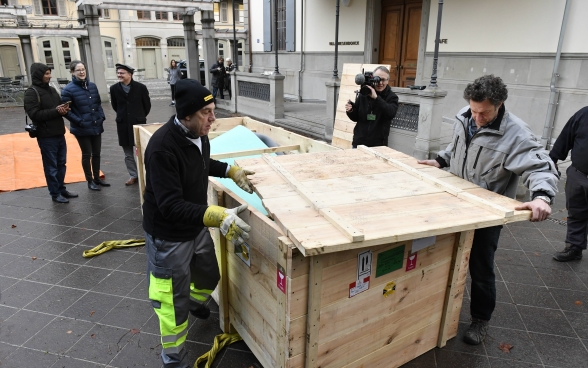 Due uomini rimuovono il coperchio del contenitore di legno contenente la statua.