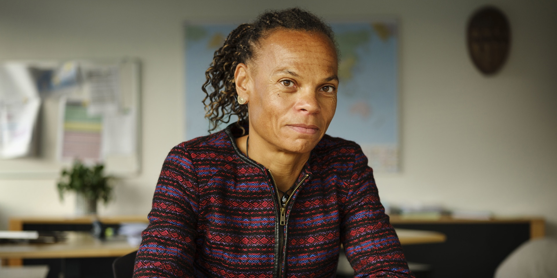 In the picture we see SDC Director General Patricia Danzi sitting at a table and looking into the camera. In the background we see her office with a map of the world on the wall.