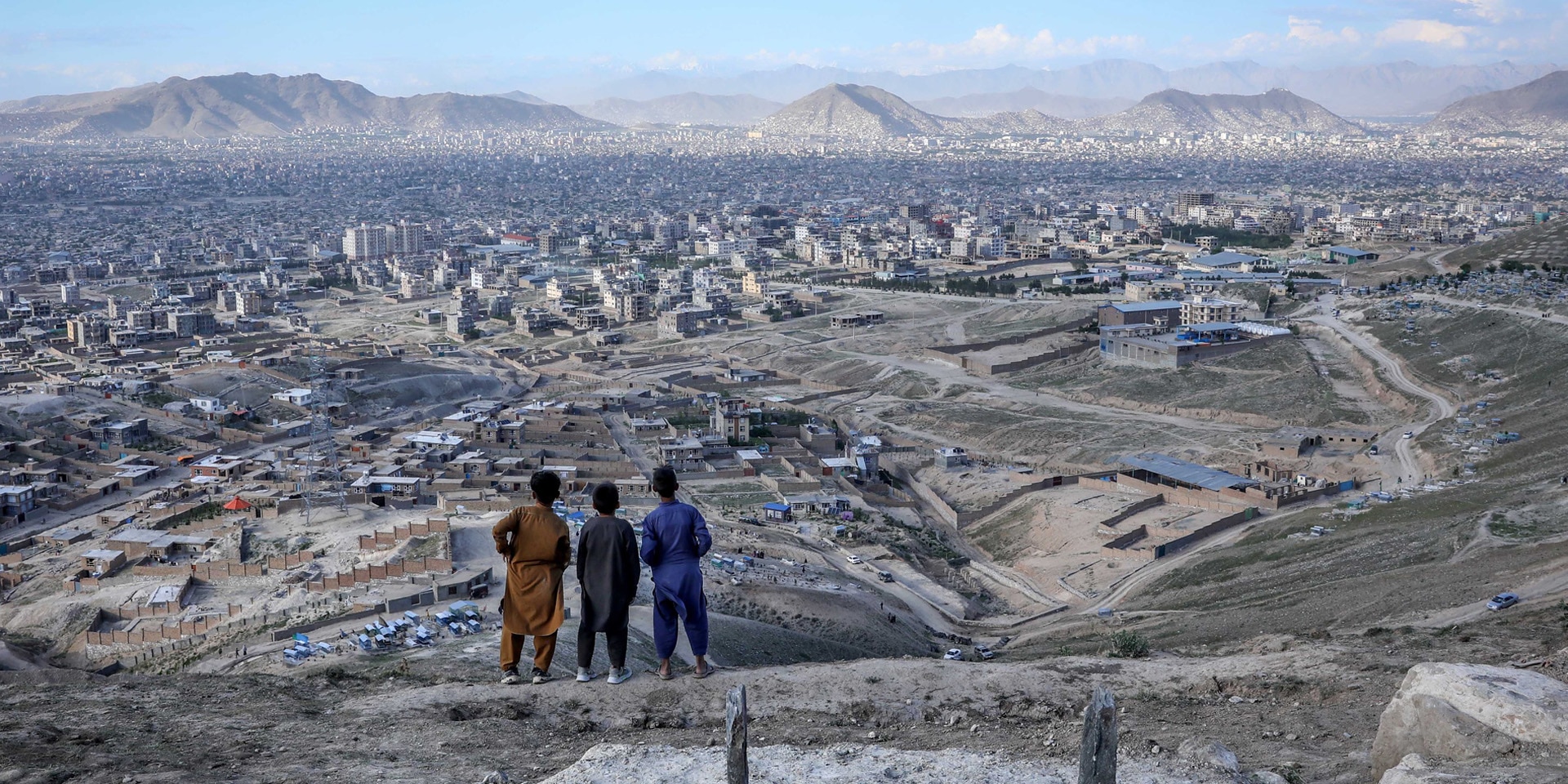 Drei Kinder schauen von einer Anhöhe auf die afghanische Hauptstadt Kabul.