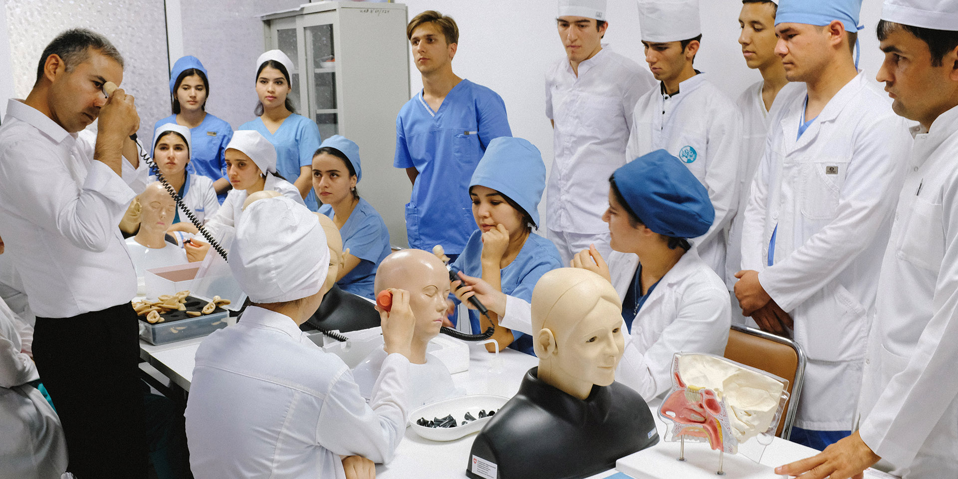 Tajik medical personnel are being trained. On the table are mannequins and medical instruments.