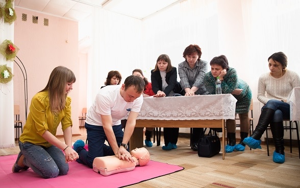Trainer shows women resuscitation techniques.