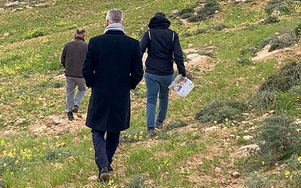 Simon Geissbühler, de dos, avance sur des collines de Masafer Yatta derrière deux autres personnes d’origine locale.