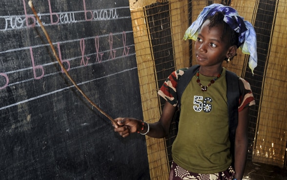 Una niña de una escuela nómada de Malí se encuentra ante una pizarra.