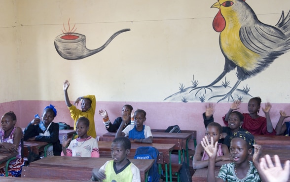 Schulklasse in Mali vor einer bunt bemalten Wand.