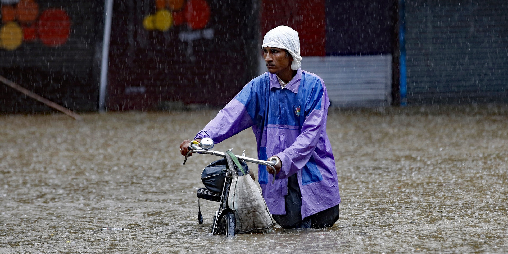A man in Mumbai, India, pushing his bicycle through floodwater..
