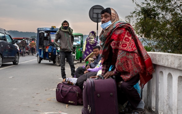 Sur le bord d’une route, des Népalais munis de leurs valises se préparent à migrer vers l’Inde.