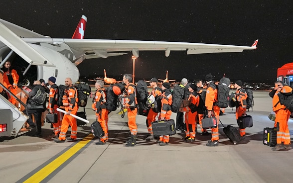 Etwa zehn Mitglieder der Rettungskette stehen vor der Treppe zum Flugzeug.