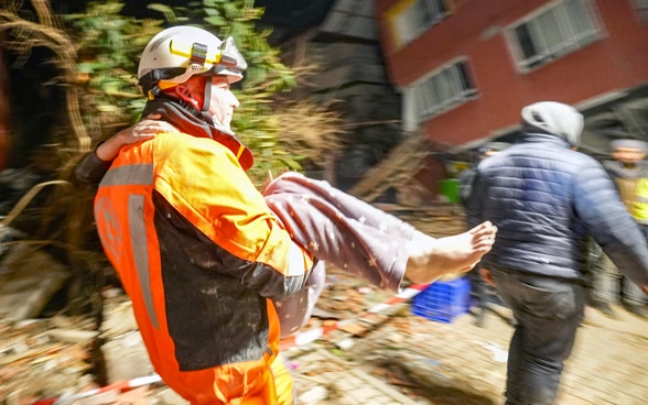 Ein Mitglied der Rettungskette trägt ein Mädchen, das soeben gerettet wurde.