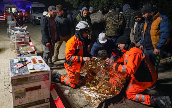 Mitglieder der Rettungskette knien neben einem Mädchen, das soeben gerettet wurde.