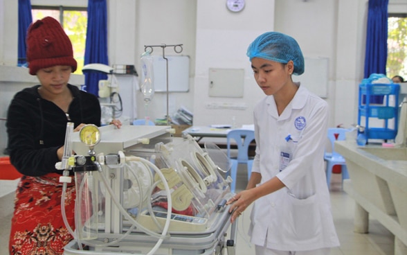 Entbindungsklinik in Siem Reap: Pflegende und Mutter vor dem Neugeborenen. 