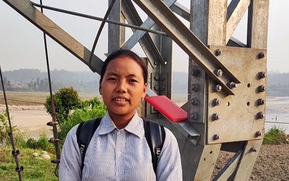 Eine Schülerin aus Nepal steht auf der Hängebrücke.